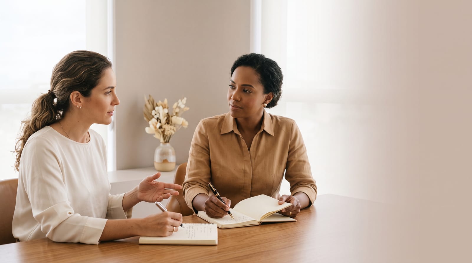 Duas mulheres à mesa, com cadernos de anotações abertos